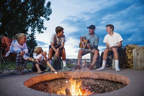 usa, utah, garden city, father with children sitting in front of campfire and playing guitar
