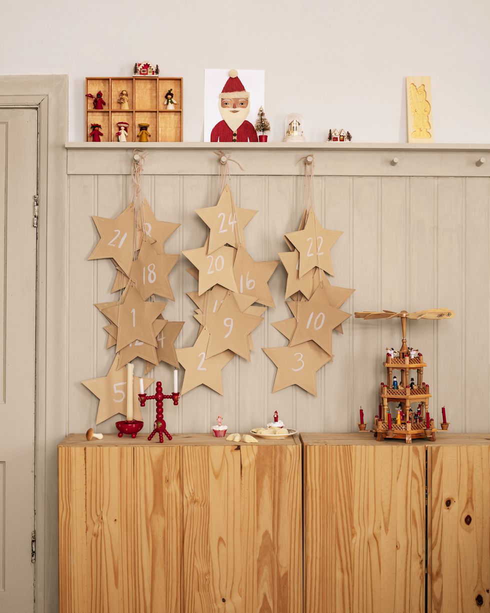 'tis a gift to be simple homeowners merrilee liddiard and jon liddiard the “star of wonder” advent calendar counts down by way of oversize paper pocket stars draped by various lengths of twine download available at merrileeliddiardshopcom christmas decor, holiday