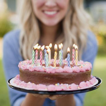mid section of young woman holding birthday cake