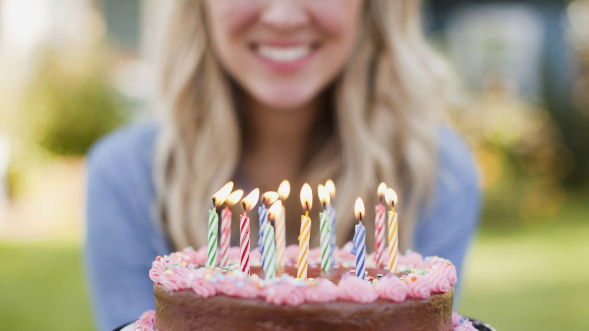 mid section of young woman holding birthday cake