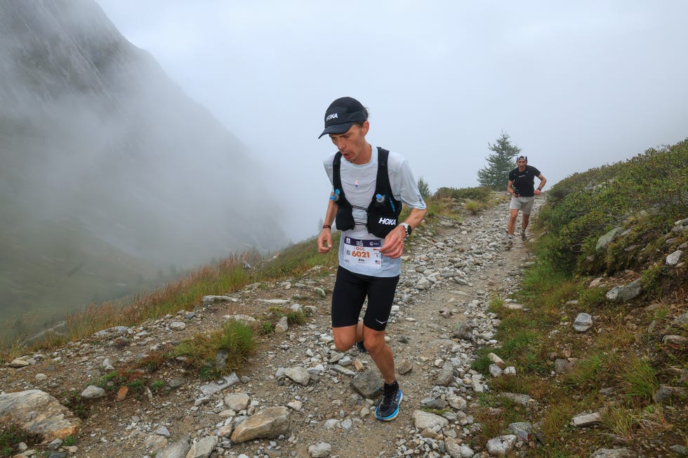 trail runners navigating a rocky mountain path in foggy conditions