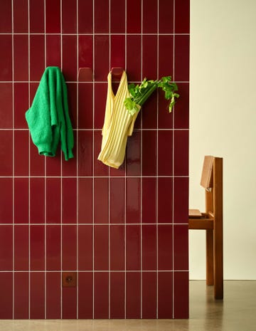 a vibrant wall holding clothing and celery complemented by a wooden chair