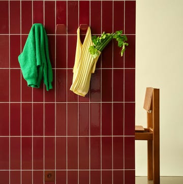 Wall hook by Unknown, Untitled a vibrant wall holding clothing and celery complemented by a wooden chair