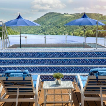 an outdoor pool area overlooking a scenic landscape featuring blue umbrellas and loungers an outdoor pool area overlooking a scenic landscape featuring blue umbrellas and loungers