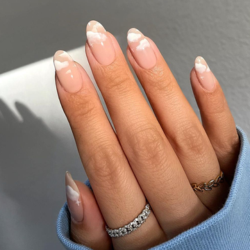 one hand in a pink border with pink nails and little white clouds and another hand on the right with pink, gray, and maroon french tips and little hearts on each nail for valentine's day