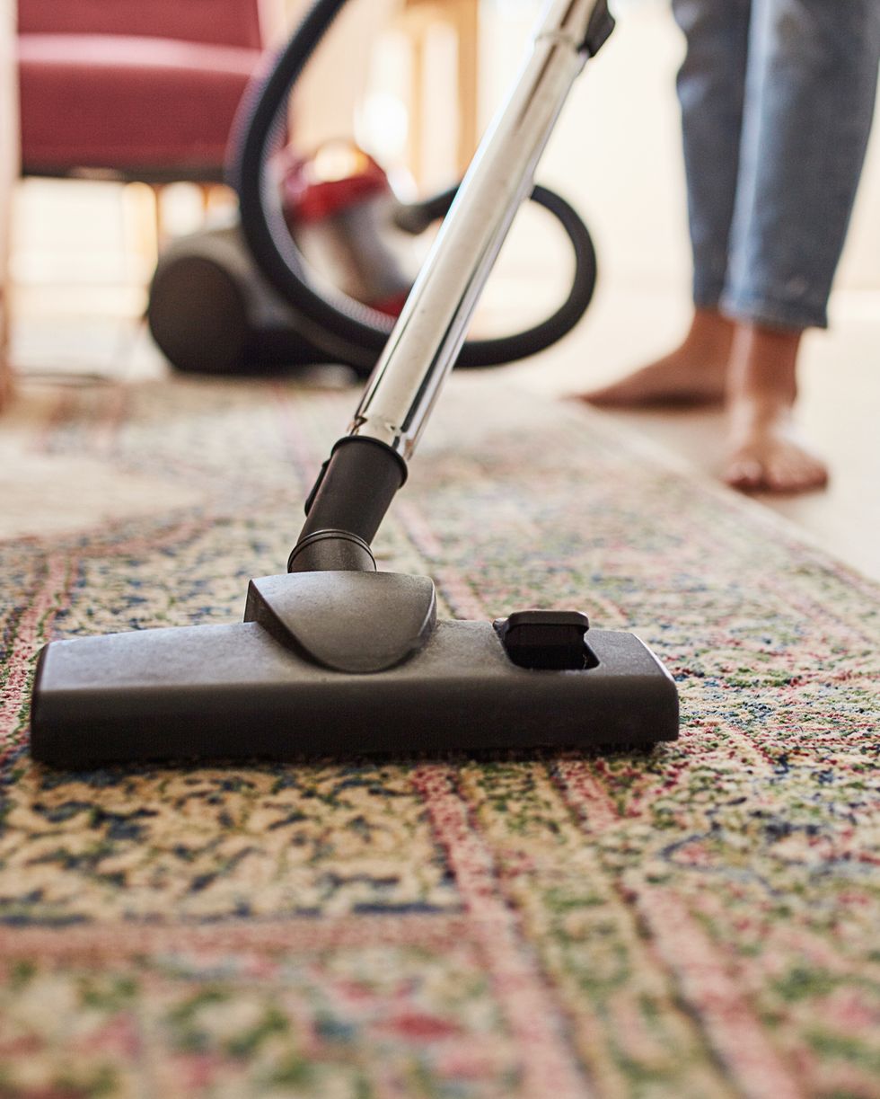 shot of a young woman vacuuming the living room at home