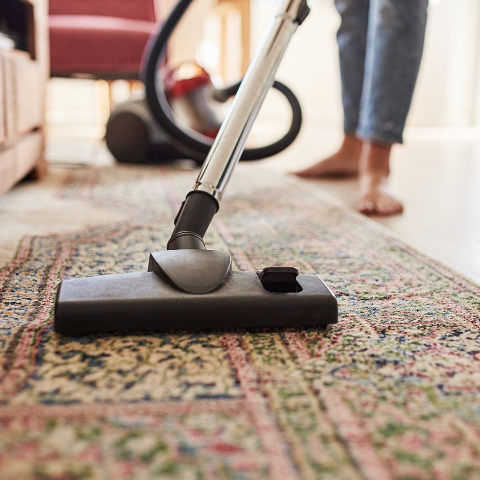 shot of a young woman vacuuming the living room at home