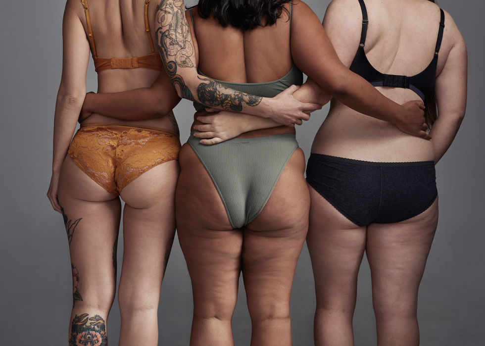 women stand in their underwear with their backs to camera