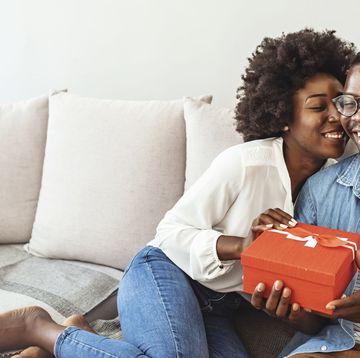 a man and a woman sitting on a couch and holding a box
