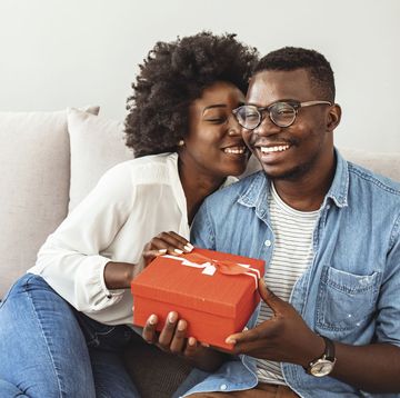 a man and a woman sitting on a couch and holding a box