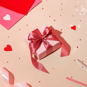 valentine day composition concept white gift box with magenta colored bow, red hearts confetti and pink paper on pastel background high angle view, flat lay