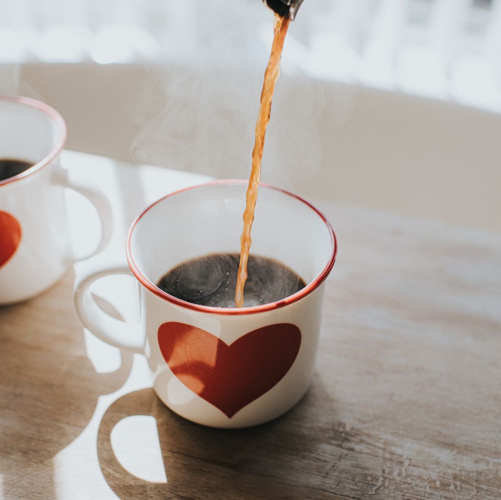 pouring black coffee into coffee cups with heart design space for copy conceptual