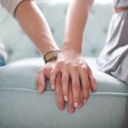 waist photo of man and woman holding hands while sitting on a couch