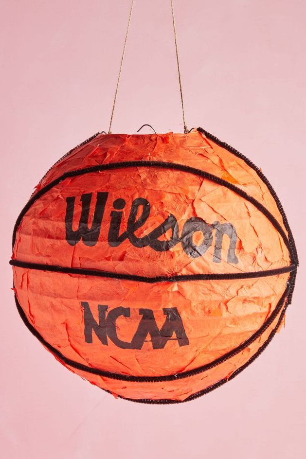 spherical valentine box decorated to look like basketball with orange tissue paper, wilson logo, and black paper cleaners