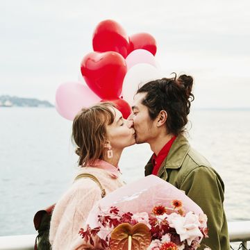 couple holding heartshaped balloons kissing while exploring city