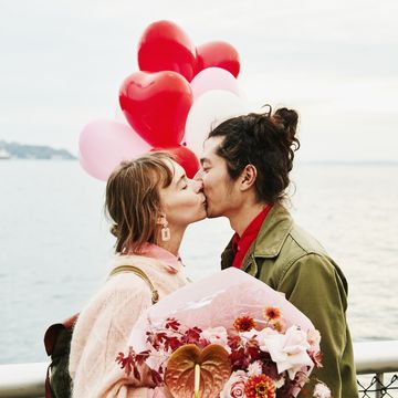 couple holding heartshaped balloons kissing while exploring city
