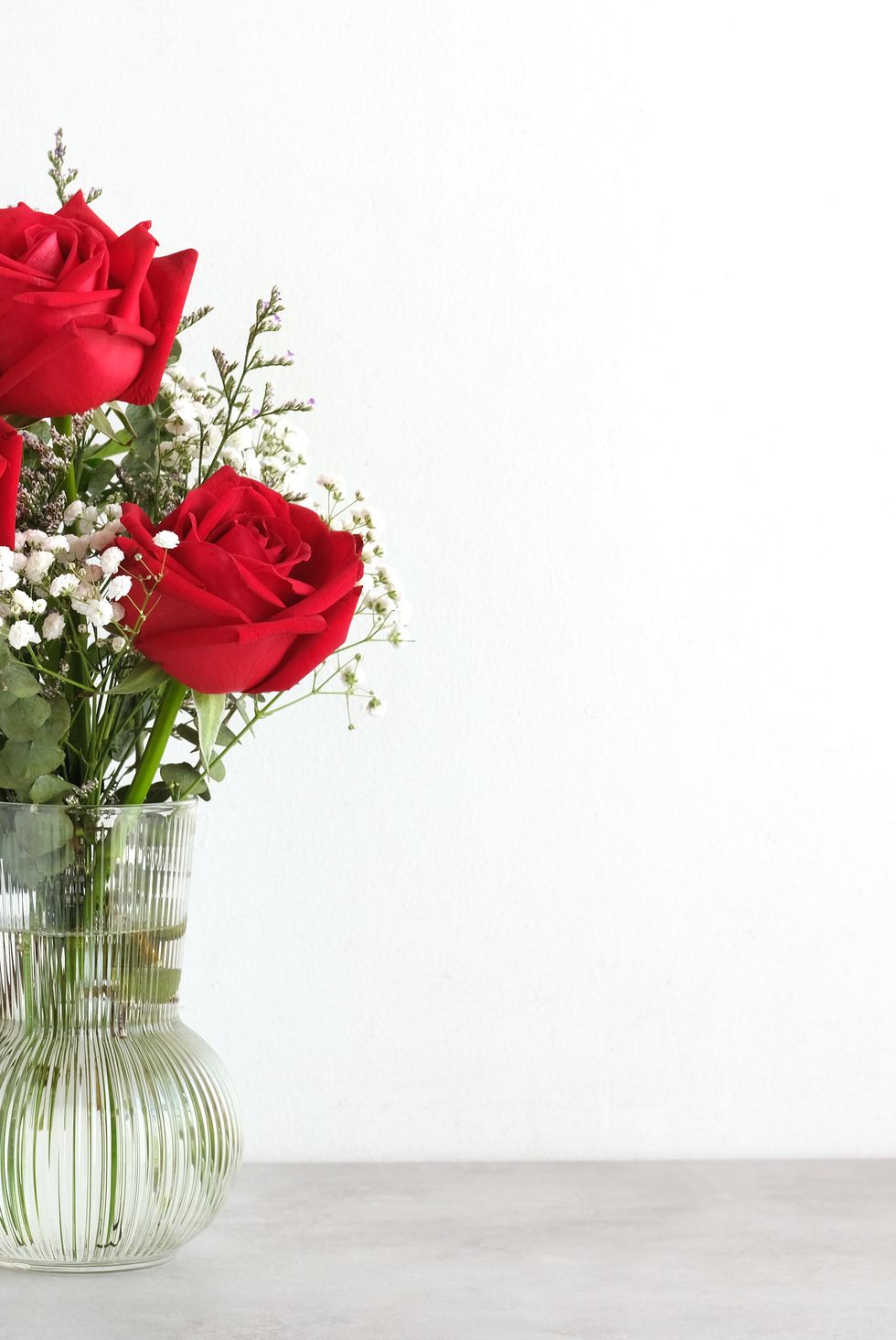 valentine’s day concept, red roses flower bouquet in glass vase on table background with copy space , banner for mock up, template