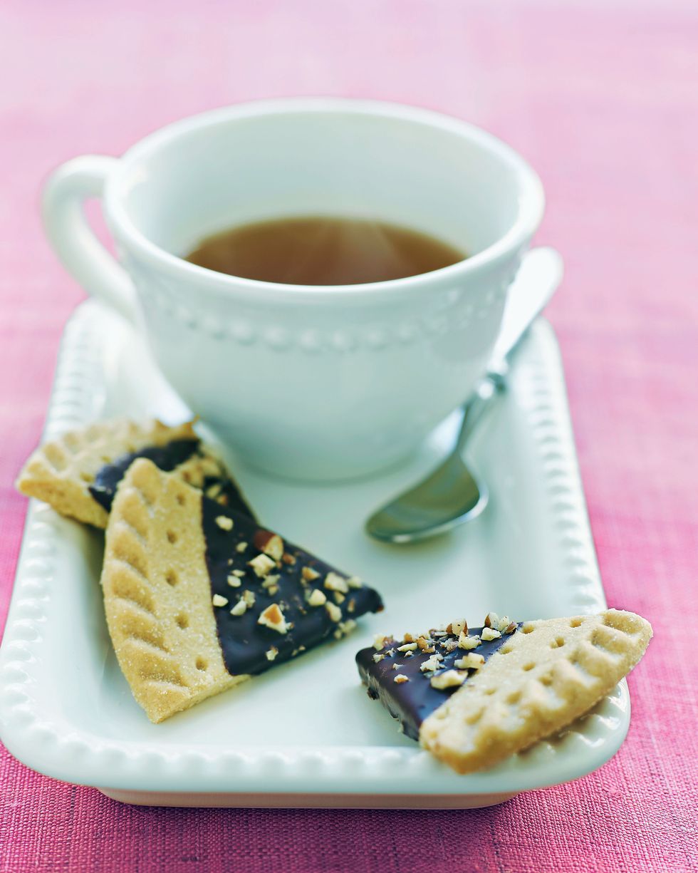 chocolate dipped cookies arranged on a plate with a cup of tea
