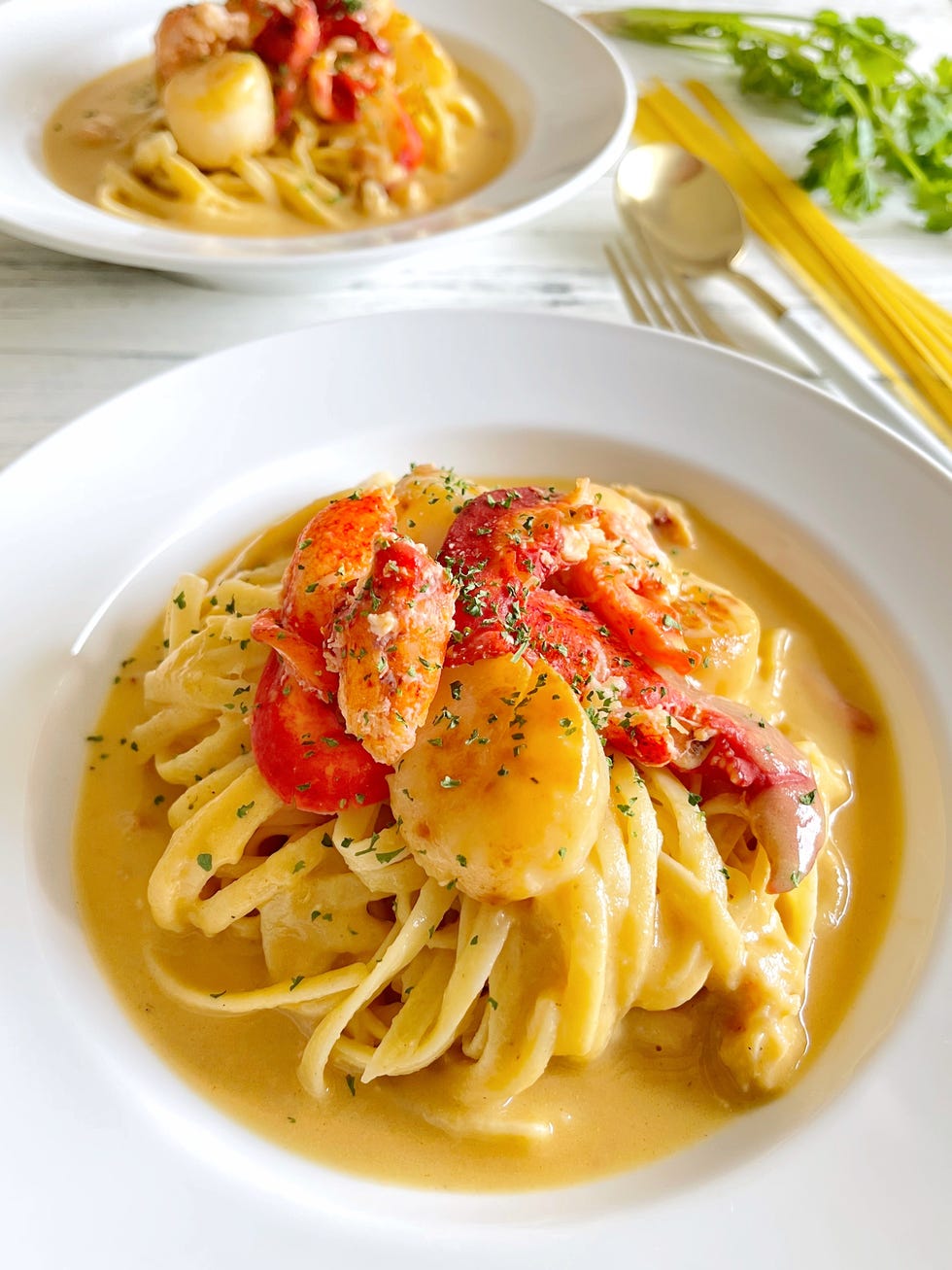 close up of a home cooked lobster and scallops linguine pasta with lobster bisque soup