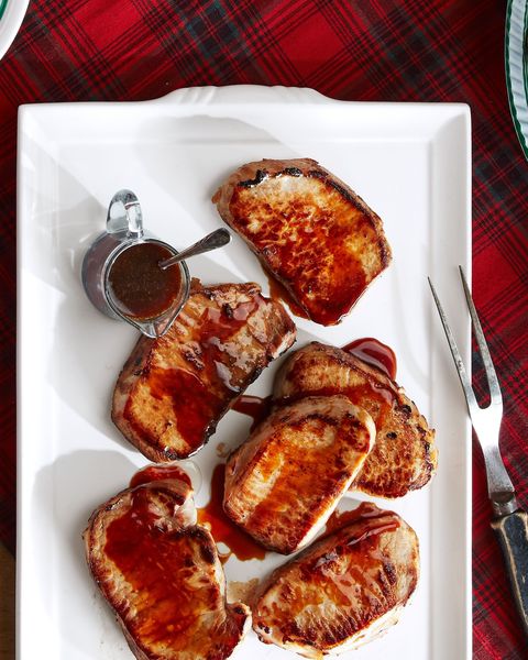 pork chops with bourbon molasses glaze on a white serving plate with a small cup of additional glaze