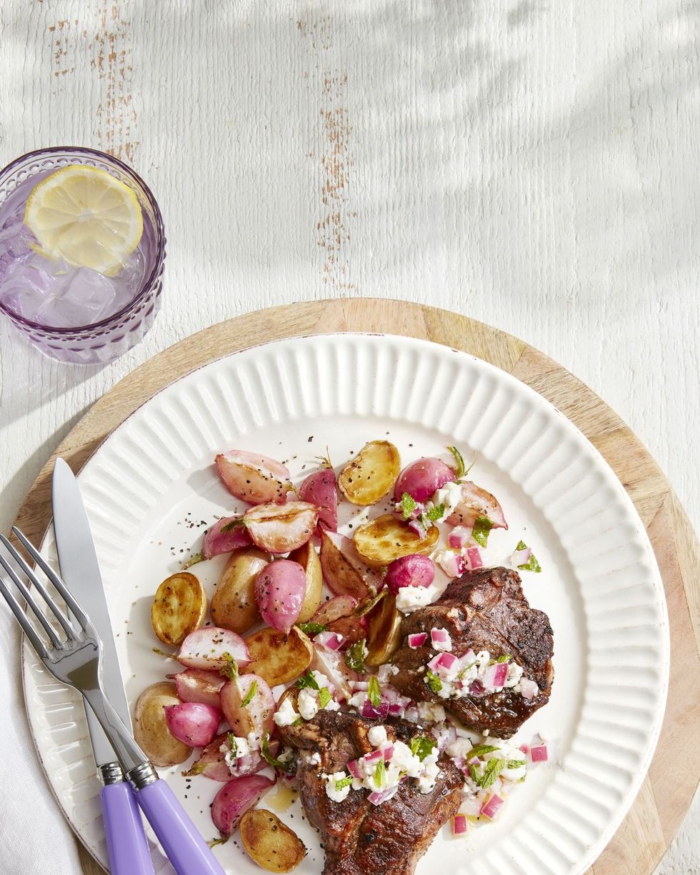 lamb chops with roasted potatoes and radishes on a white plate with silverware