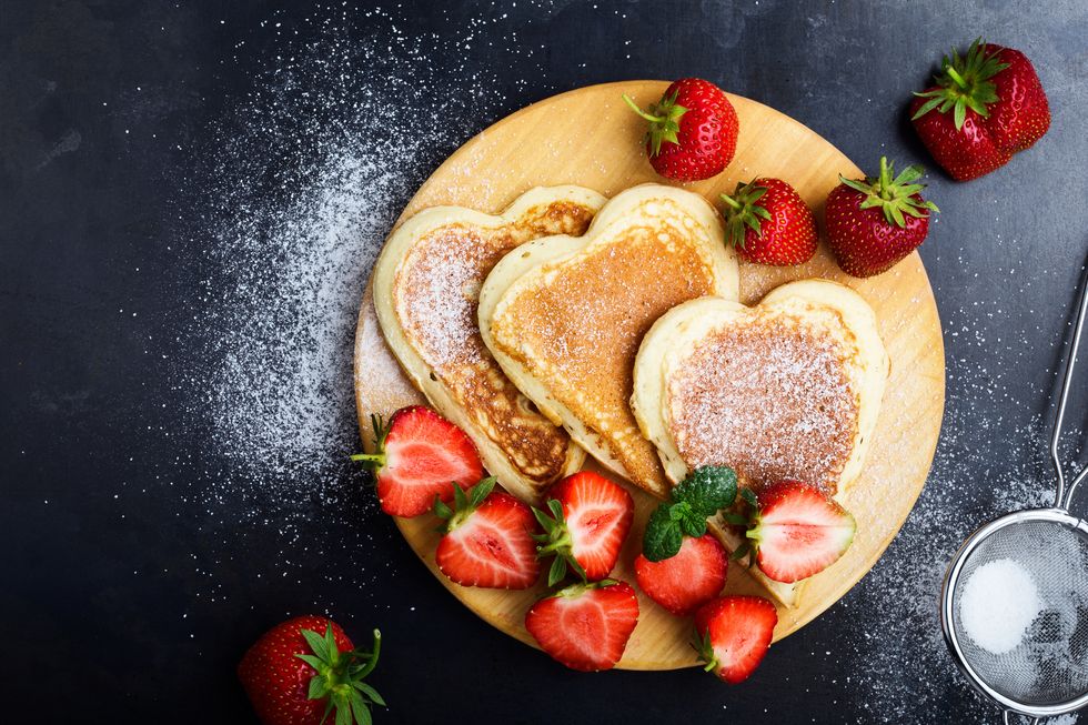 valentines day breakfast table with heart shaped pancakes and strawberries, top view