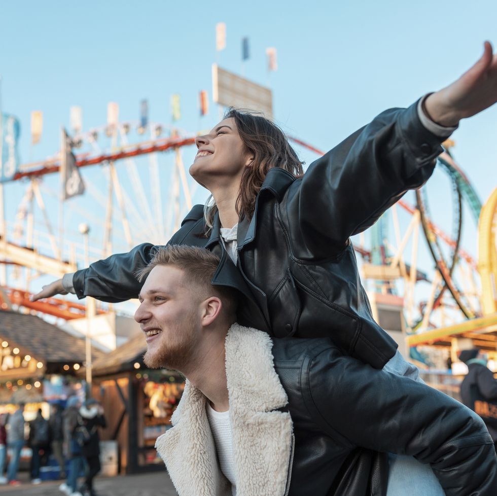 a man and woman posing for a picture in front of a carnival ride