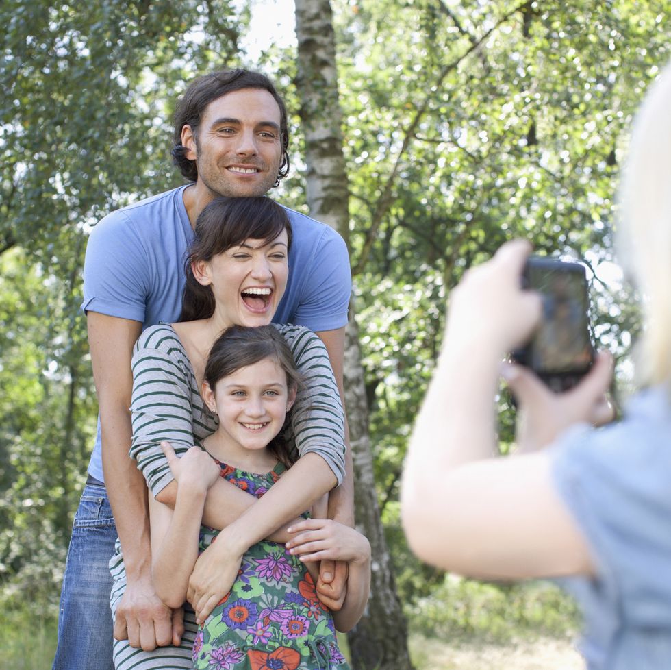 parents with daughter posing for photograph taken by another daughter