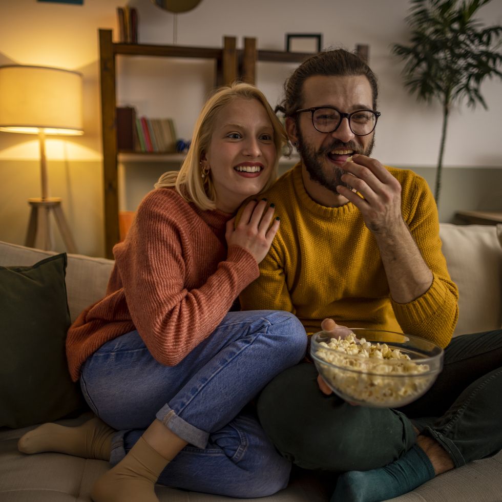 couple watching tv and eating popcorn