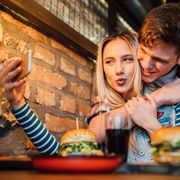 young couple making a selfie while having lunch at the pub