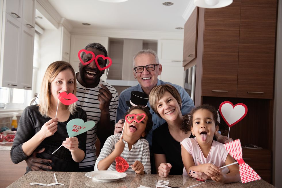 mixed race family father mother little daughter and son grandmother and grandfather doing photobooth during valentines day photos was taken in quebec canada this photo can be use also for mothers day, fathers day or birthday can also use for modern family brief 679006863