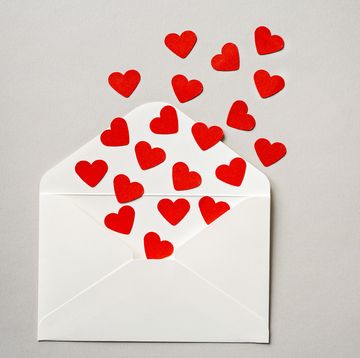 white open envelope filled with red cutout hearts