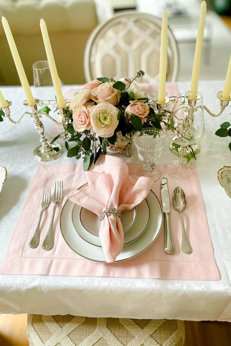 a table with a pink and white cloth and silverware