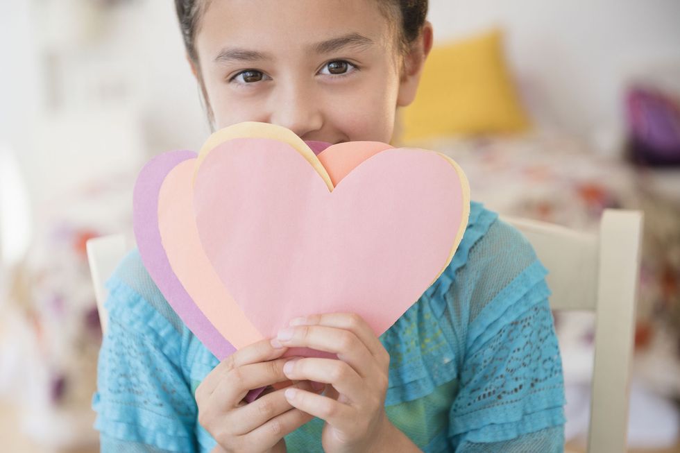 girl with construction paper hearts in front of her face
