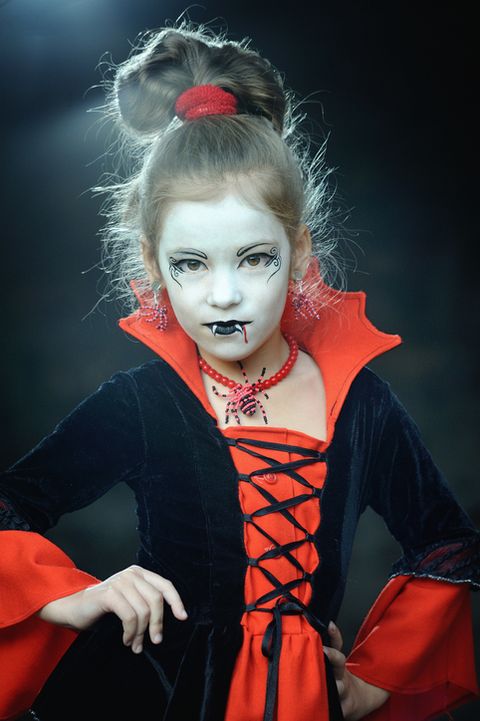 a little girl in vampire styled fancy costume posing