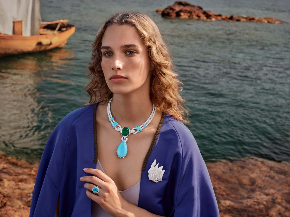 model stands on rocks by the sea wearing fine jewels