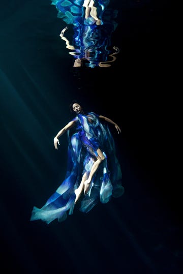 a person submerged in water wearing flowing blue fabric