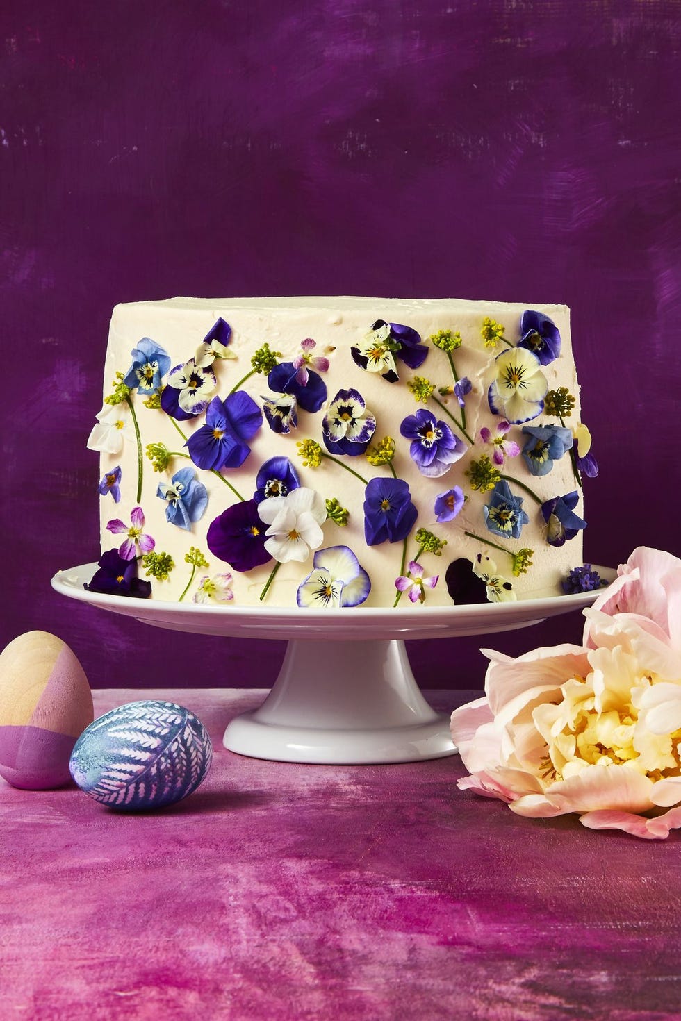 vanilla blossom cake with edible flowers on a white cake stand