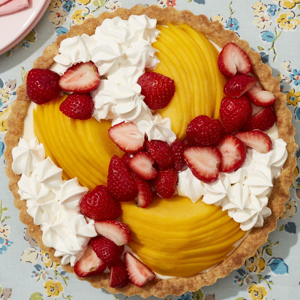 vanilla tart topped with mango slices strawberries and whipped cream