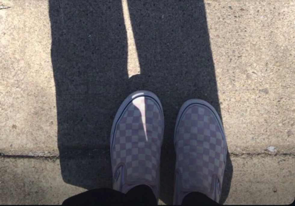 someone wearing vans classic slip on checkerboard sneakers on pavement