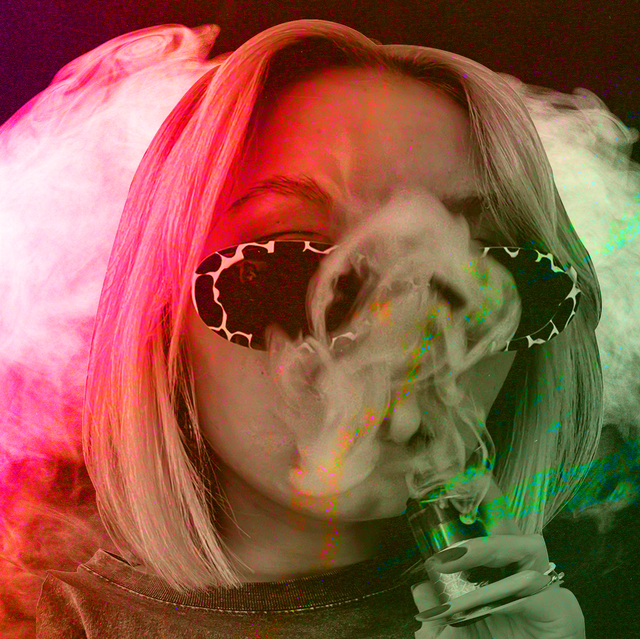 a woman in sunglasses, shrouded in red and green smoke as she vapes