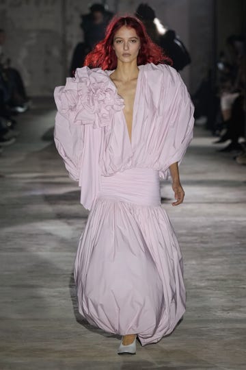 Fashion model showcasing avantgarde pink dress on runway
