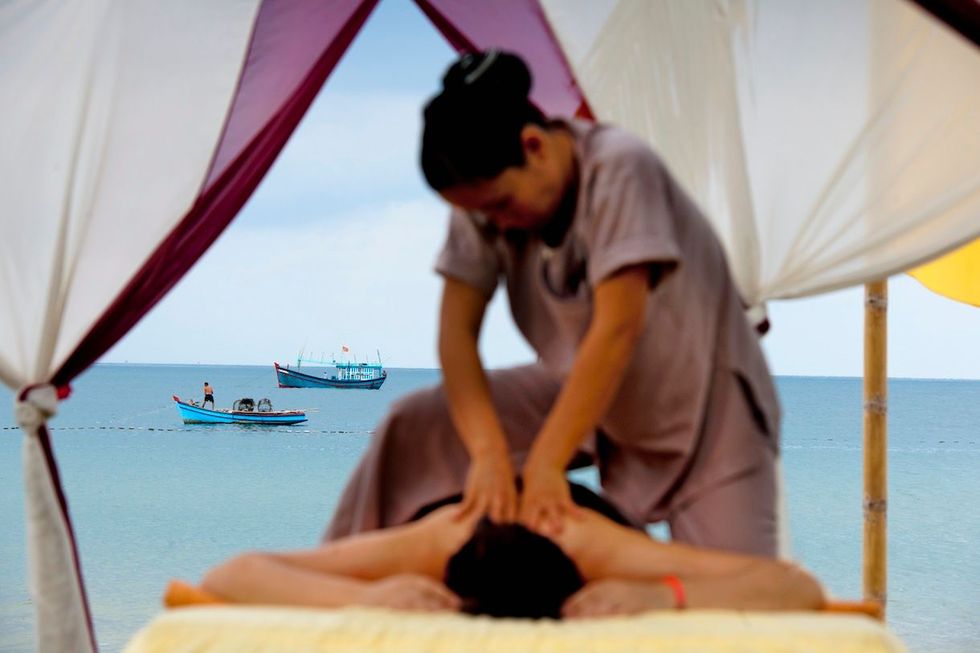 Een bezoeker geniet van een massage aan het strand van Phu Quoc de perfecte plek om uit te rusten en indrukken te verwerken