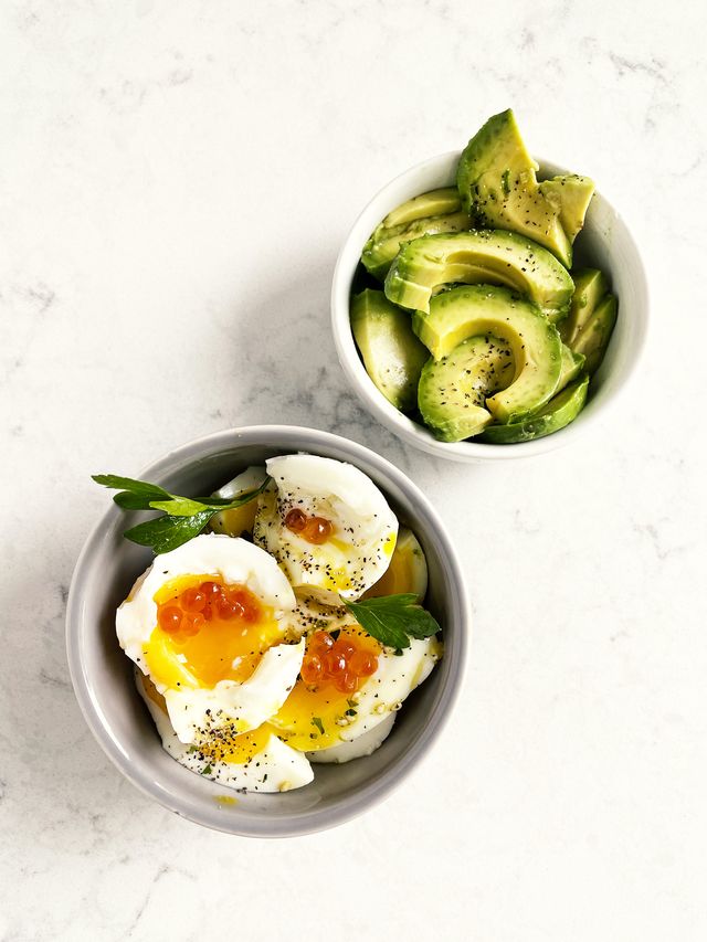 variety of appetizers boiled eggs, and avocado on white background