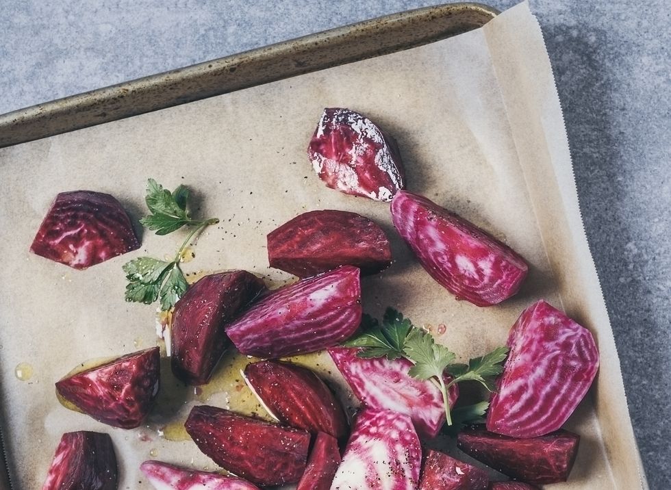 variety of sliced beets on a baking sheet on gray background