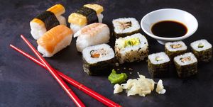 Variety of sushi with wasabi, ginger and bowl of soy sauce on dark ground