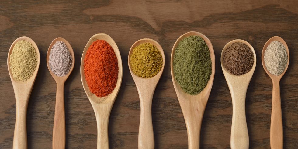 various colorful spices on wooden spoons