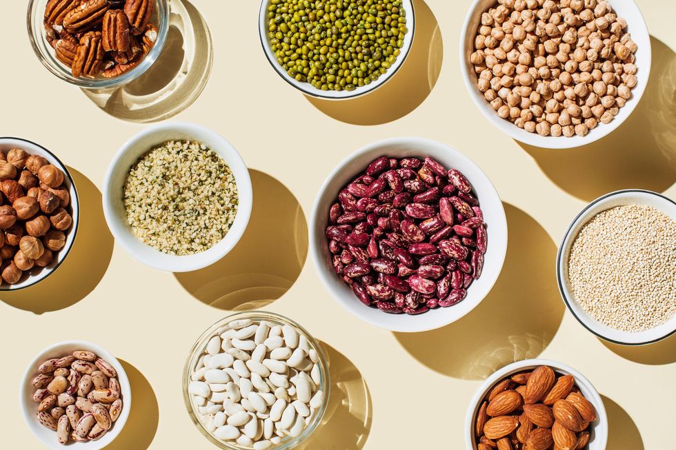 various kinds of vegan protein sources on beige background set of food supplements gluten free cereals as ground hemp seeds, quinoa nuts and legumes green mung beans, chick pea, red lentil, kidney bean, almonds, hazelnuts flat lay, top view