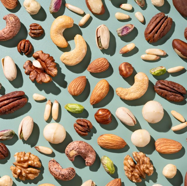various nuts flat lay on green background