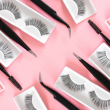 various tools for eyelash extensions on trendy pastel pink background concept fake eyelashes, tweezers and brush makeup accessories cosmetics